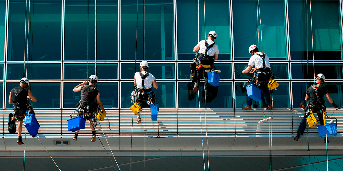 hombres realizando servicio de limpieza de alturas a una ventana de un edificio