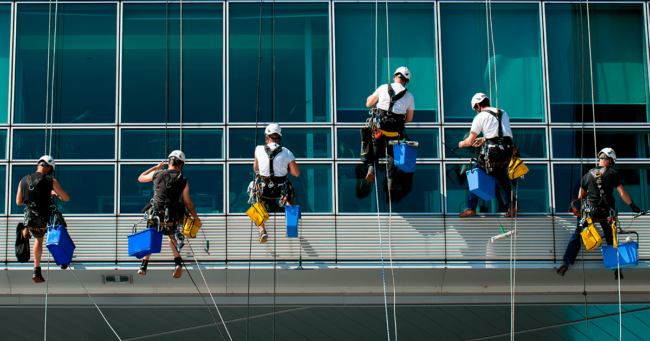 hombres realizando servicio de limpieza de alturas a una ventana de un edificio