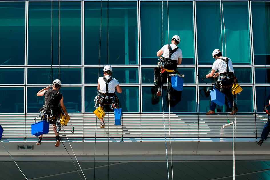 hombres realizando servicio de limpieza de alturas a una ventana de un edificio